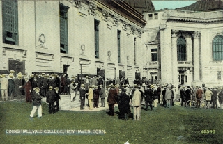 Postcard of Hewitt Quadrangle featuring men from the 1920s wearing boater hats on a green lawn