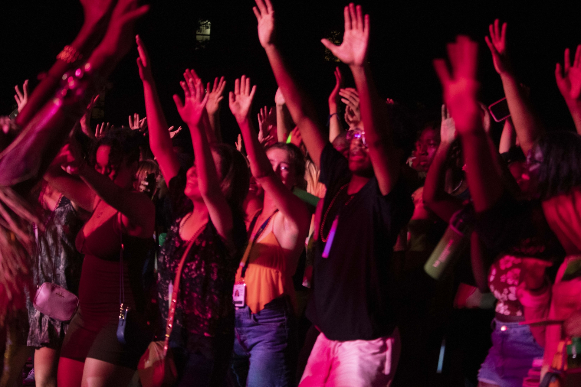 students with hand raised presumably at an outdoor evening concert