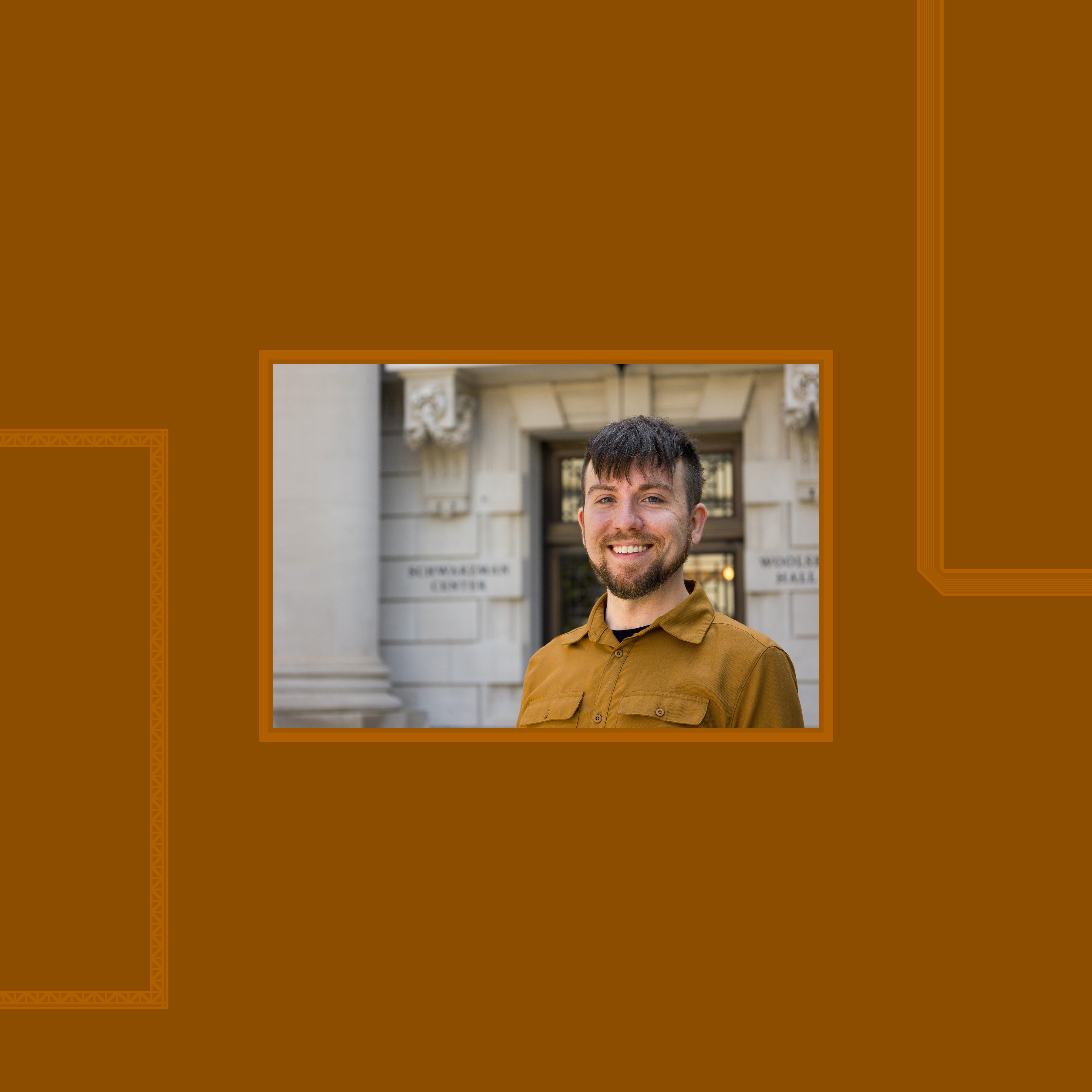 Man smiling in warm rust color shirt in front of column.