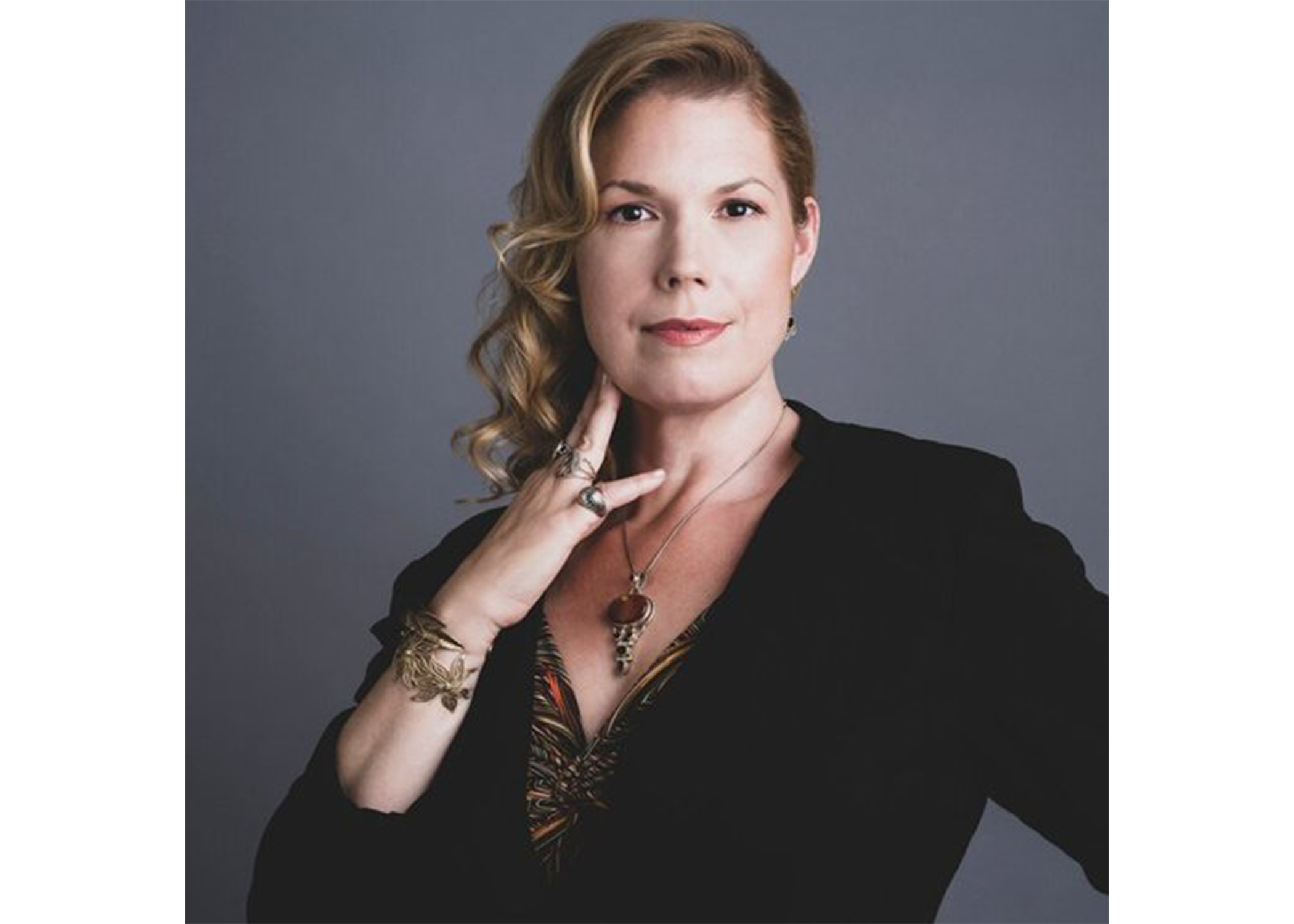 Portrait photo of a blonde woman posing with her hand on her neck