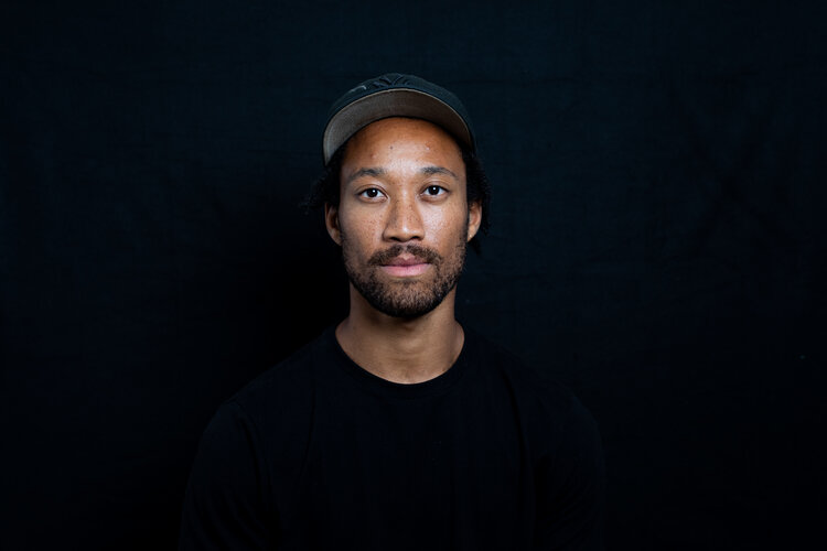 Raymond Pinto on a black backdrop. Looks directly at the camera.