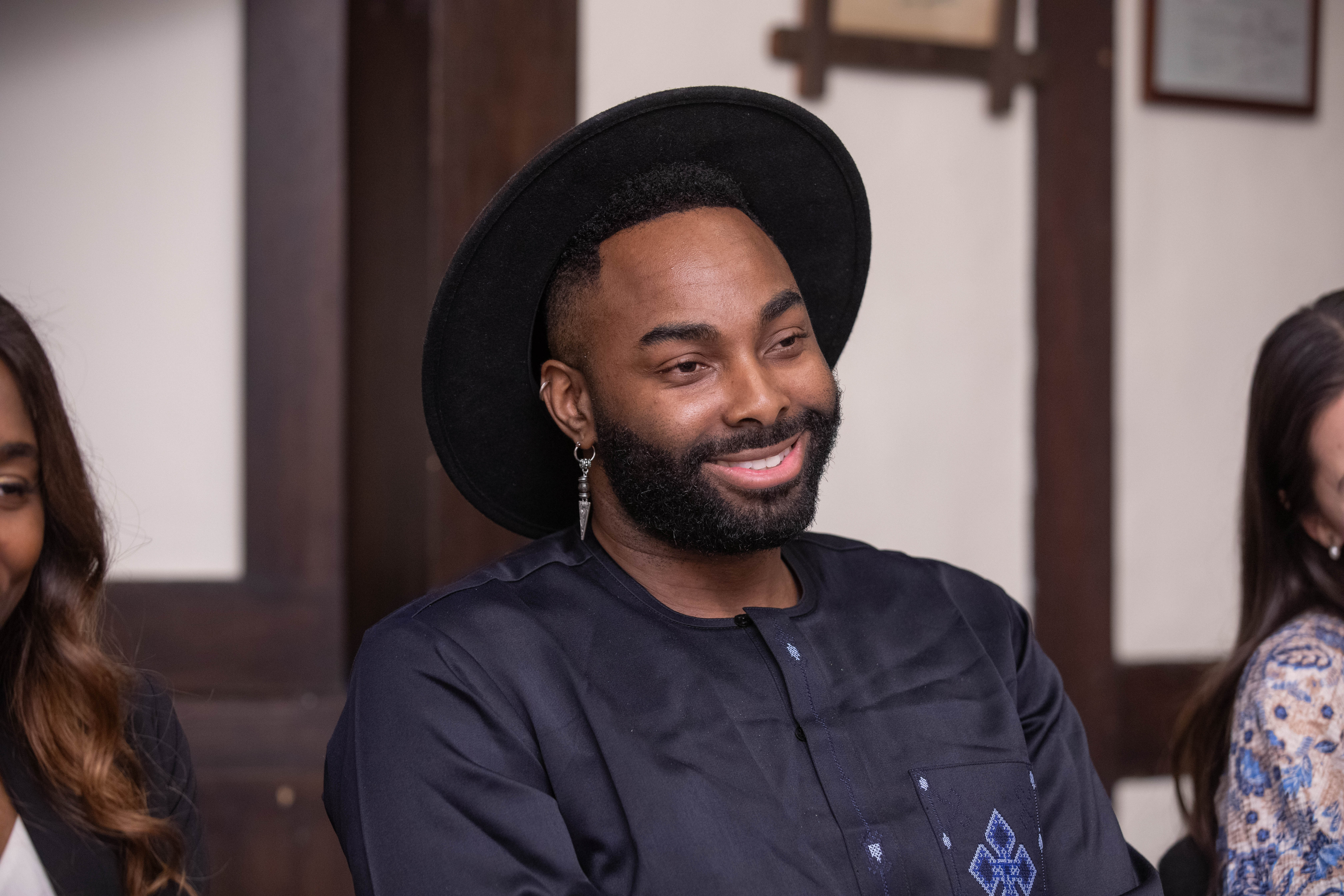 Headshot. Houngan Collin Edouard wearing a hat and smiling.