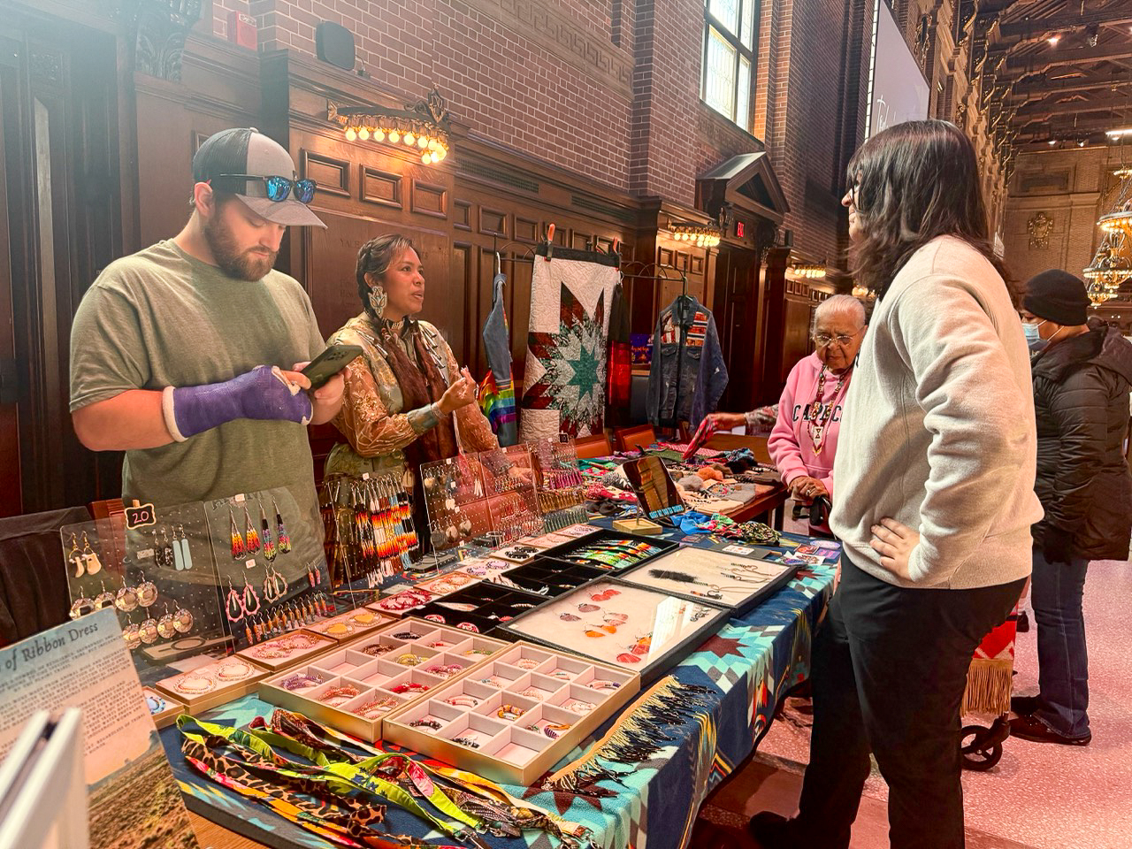People stand across from each other at vendor tables in Commons. This is during the Yale Powwow of Light.