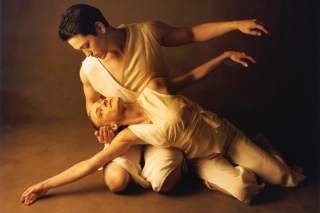 Two dancers, male and female, entwined in a kneeling pose