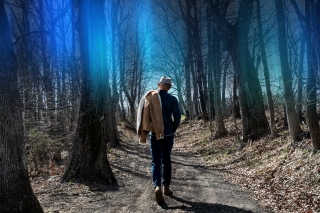 Ionne facing away from camera and walking into an indigo-highlighted forest
