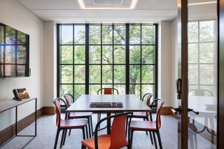 A bright, intimate room with a long table, chairs, and wall of paneled windows. Photo by Francis Dzikowski.
