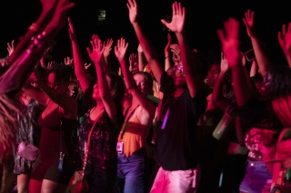 students with hand raised presumably at an outdoor evening concert