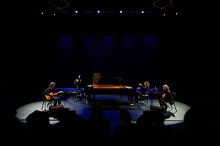 Bryce Dessner and David Chalmin play guitars on far left and right of the stage with Marielle and Katia Lebeque play grand pianos facing each other center stage.