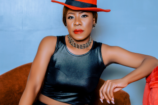 Lady Jaydee in a Red hat and black leather crop top.