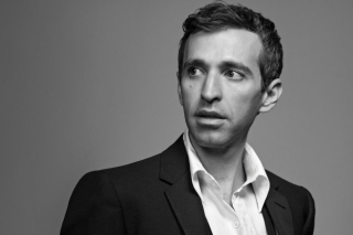 Black and white headshot, jacket and open collar white shirt.