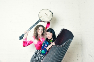 Two artists pose together with their instruments creating a visually balanced fun image