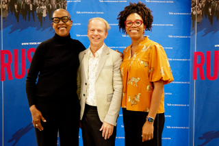 Left: Rustin costume designer and co-chair of design at the David Geffen School of Drama Toni-Leslie James, Center: Rustin Producer Bruce Cohen '83, Right:  Yale African American Studies and American Studies professor Crystal Feimster stand together smiling in front of a Rustin branded backdrop.