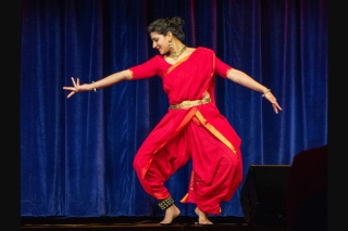 Woman in bright red outfit and striking dance pose.