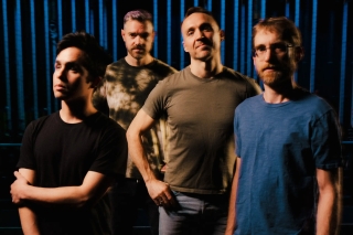 Four men in t-shirts, with distinct personality driven poses.