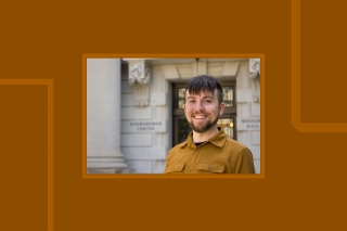 Man smiling in warm rust color shirt in front of column.