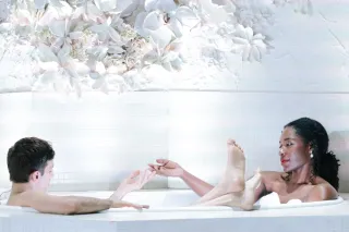 Two people in white bathtub with flowers