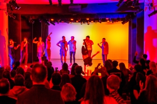 Packed crowd watches performers with breakdance moves.