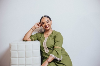 Dancer in casual seated pose with white background.