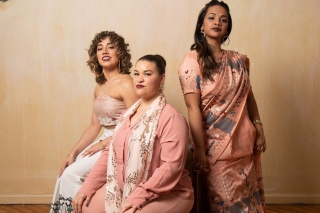 Three women in peach clothing pose together.