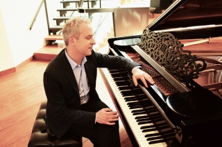 Sits in front of piano.