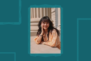 Headshot, leaning on hand, peach colored dress.