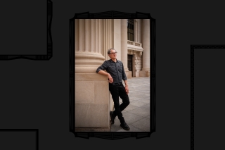 Man standing against pillar. Casual pose.