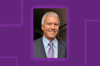 Headshot smiling. Grey suit and purple tie.