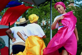 Colorful outfits. People mid dance on outdoor stage. 