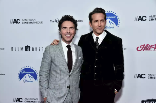 Two men in suits arm in arm. 