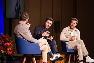 Three people on stage speaking.