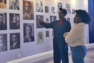 Two people observe and discuss images on a wall.