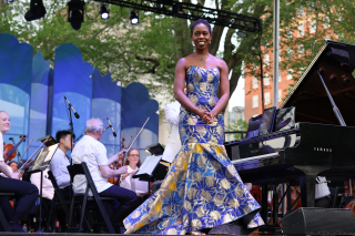 Woman in gown on stage in front of a piano.