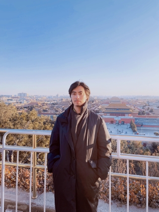 Victor Wang standing against a railing with a city skyline behind