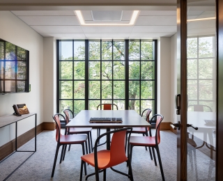 A bright, intimate room with a long table, chairs, and wall of paneled windows. Photo by Francis Dzikowski.