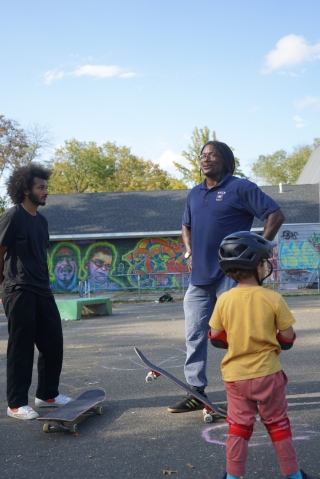 J. Joseph and Dr. Neftalie Williams chat while a young skateboarder watches on