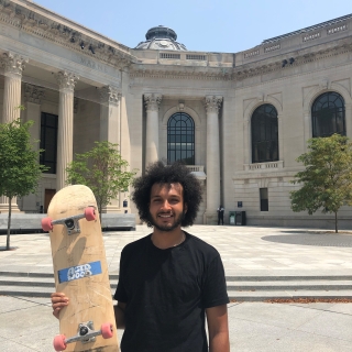 J Joseph holds his skateboard on Hewitt Quadrangle
