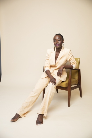 Nathalie Joachim wearing a tan pantsuit and sitting an a chair