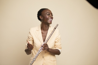 Nathalie Joachim standing, smiling, holding a flute