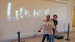 Awuor Onguru '23 & Zack Reich '26 standing in front of their projection design exhibit