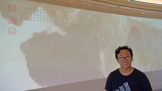 David Zheng (郑明远) '23 standing in front of his projection design exhibit