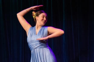 Woman in a posed dance move, in a light blue dress. 