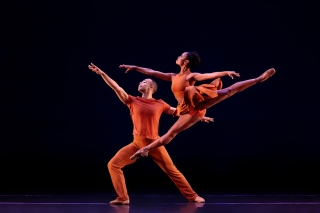 Two dancers from Dance Theatre of Harlem, male and female, in red costumes on a dark stage