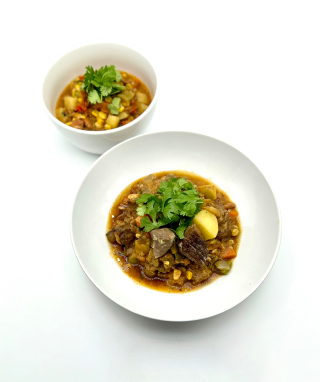 Three sisters stew in a small white bowl and lamb stew in a large white bowl