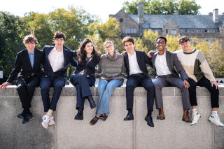 Seven undergraduate students (members of Yale Undergraduate Jazz Collective 2025) sitting on a wall