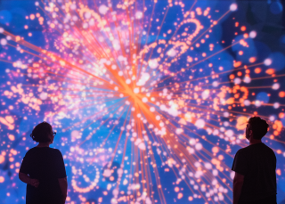 People observe a light projection in oranges and blues